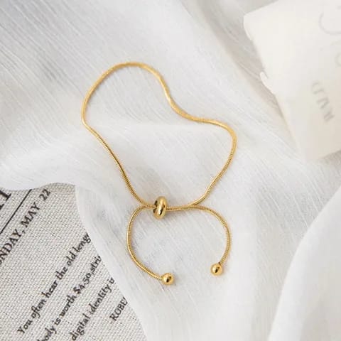 Gold bracelet on a white surface with text underneath