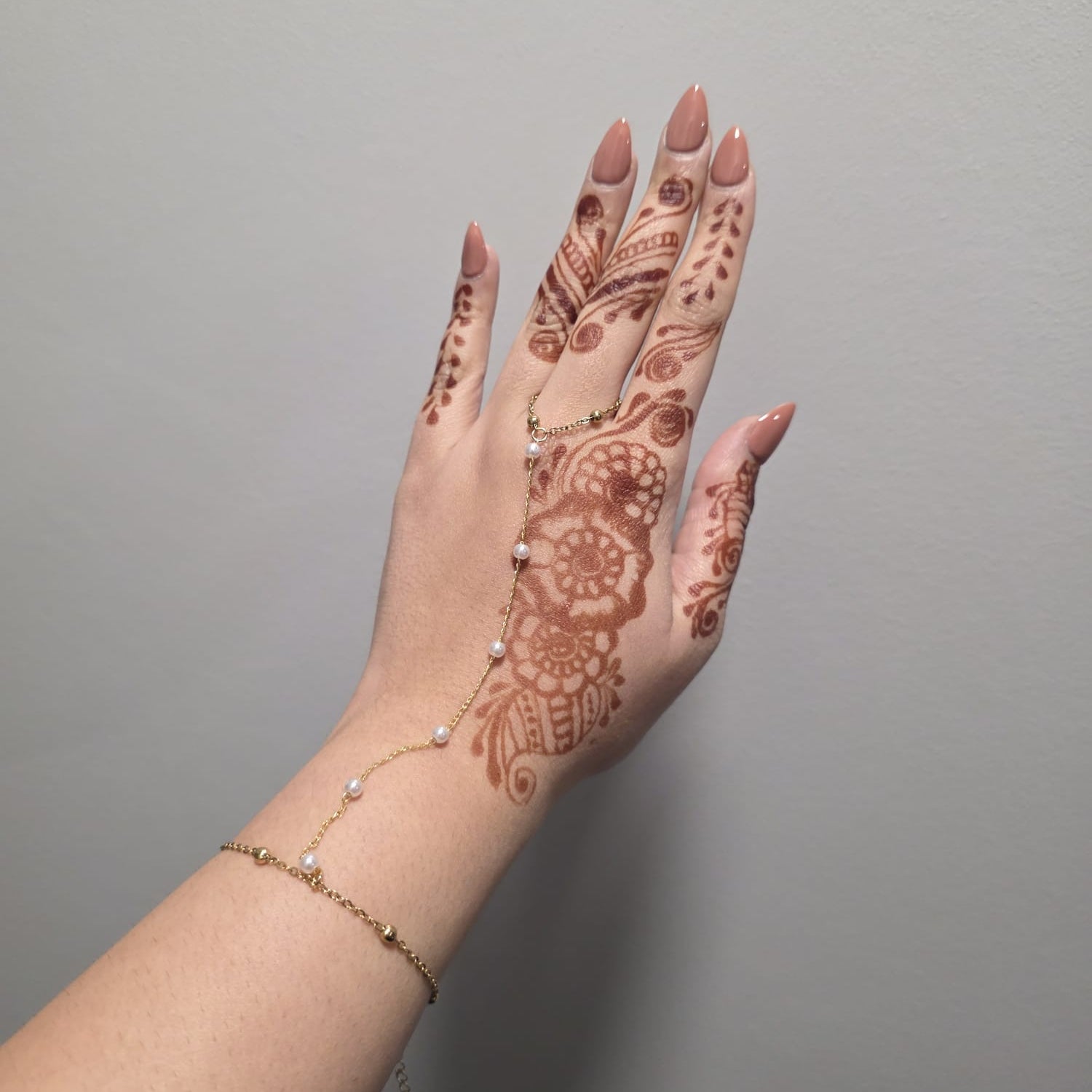 Hand with intricate henna design on a plain background