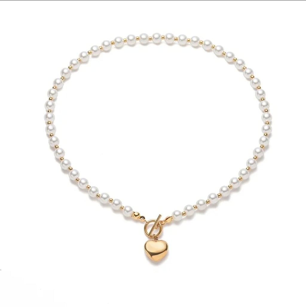 Pearl bracelet with a gold heart charm on a white background
