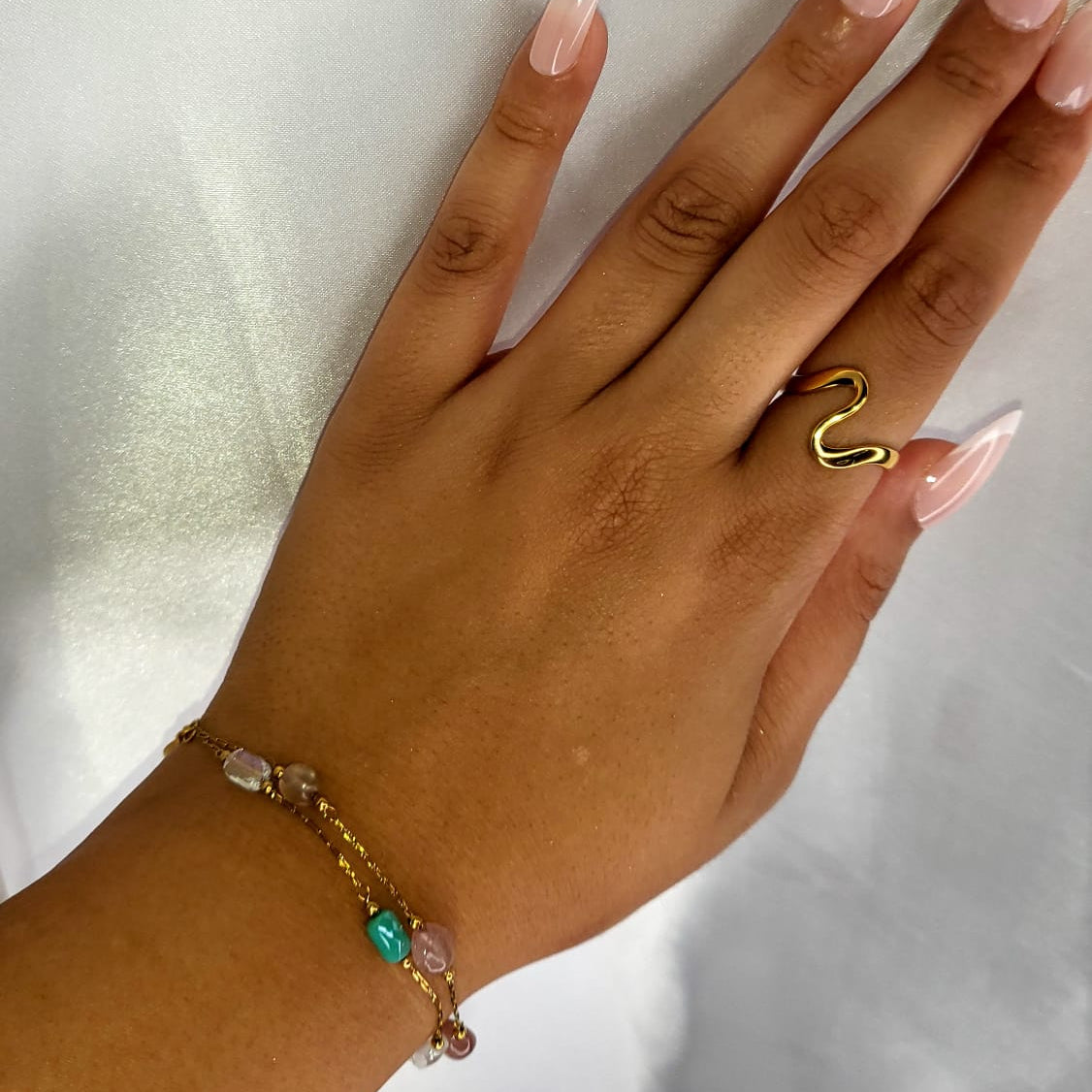 Hand wearing a gold ring with a heart-shaped design on a white background