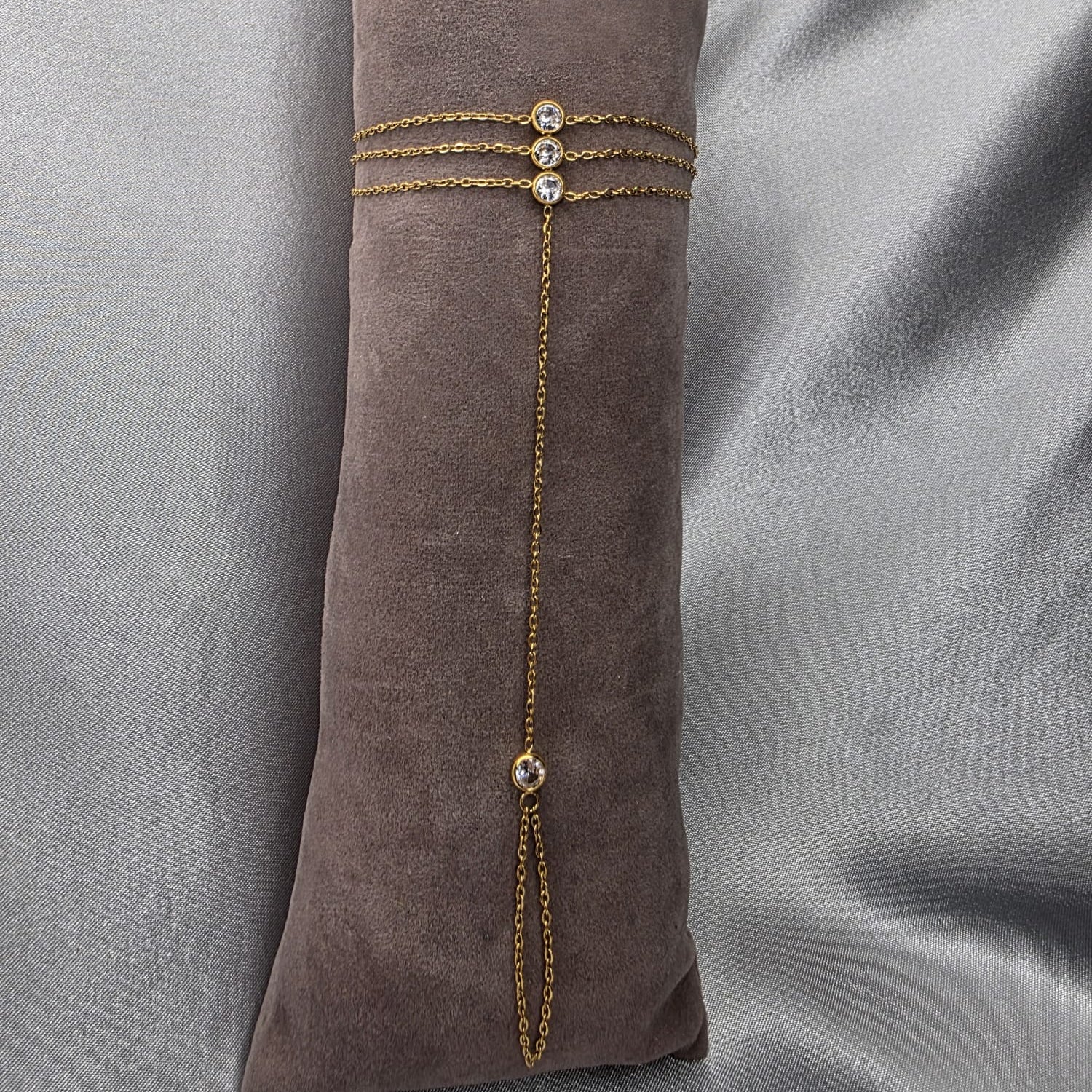 Gold bracelet with gemstones on a brown fabric background