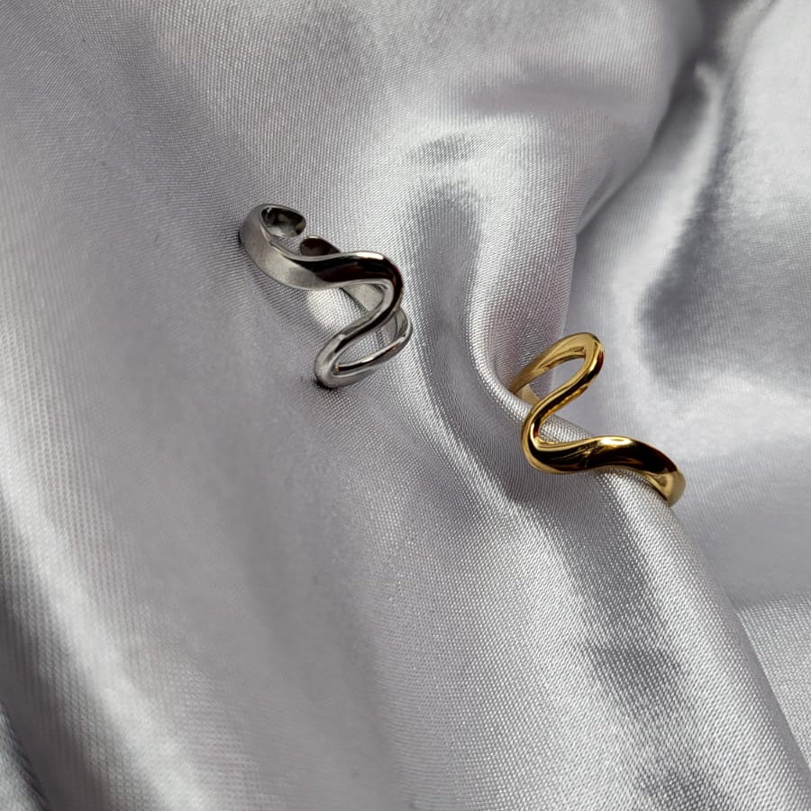 Two rings, one silver and one gold, on a satin surface.