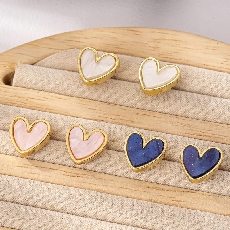 Heart-shaped earrings with gold rims on a wooden display