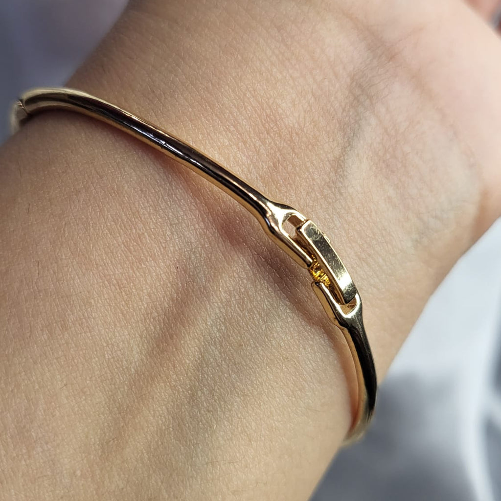 Gold bracelet on a wrist with a blurred background