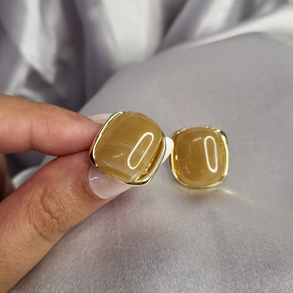 Gold ring held by a hand on a light gray fabric background