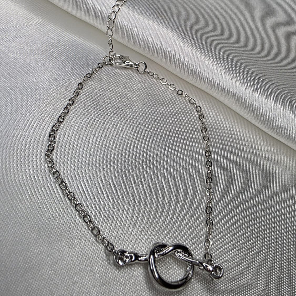 Silver bracelet on a light gray fabric background