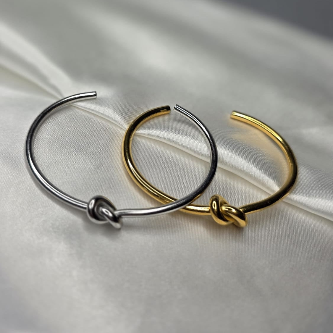 Gold and silver hoop bangles on a white fabric background