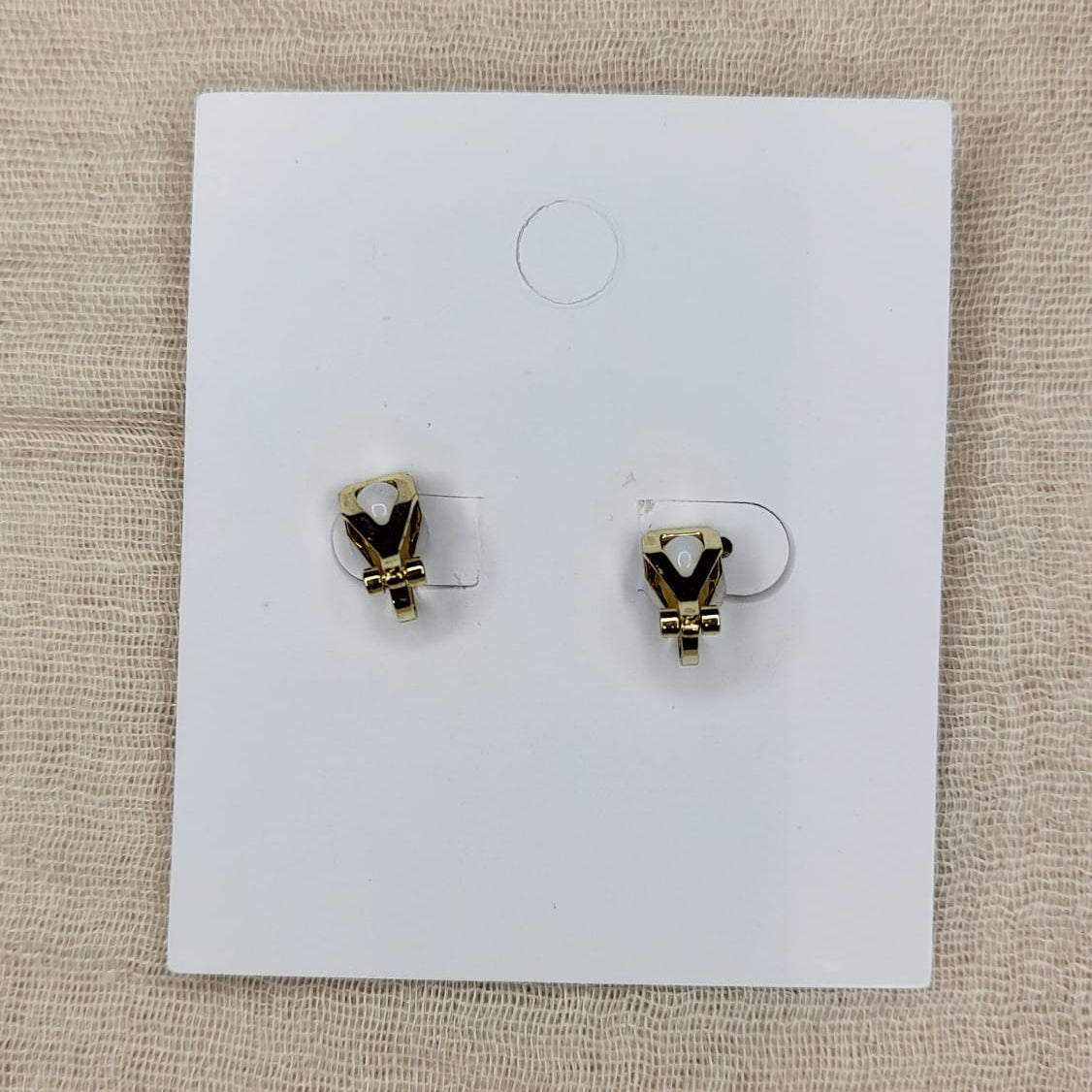 White heart earring clip on back, on a white card with a beige background