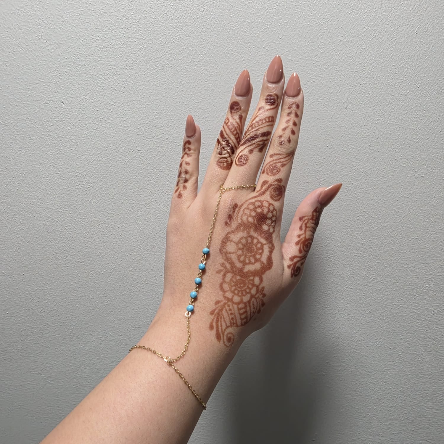 Hand with intricate henna design on a plain background