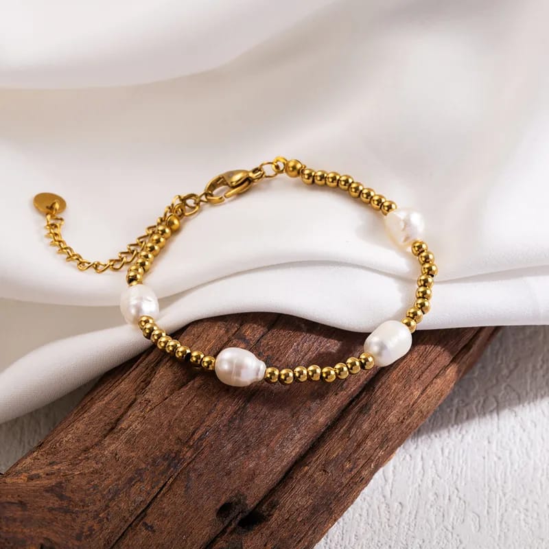 Gold bracelet with pearls on a white surface