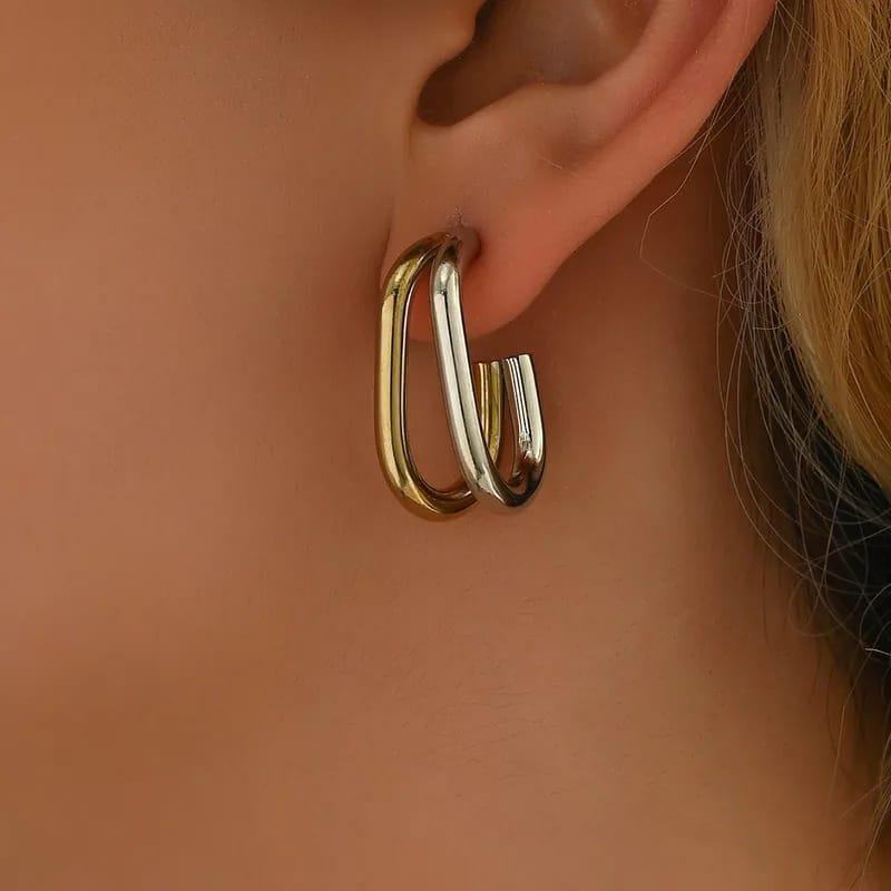 Gold/silver  hoop earrings worn on an ear with a neutral background